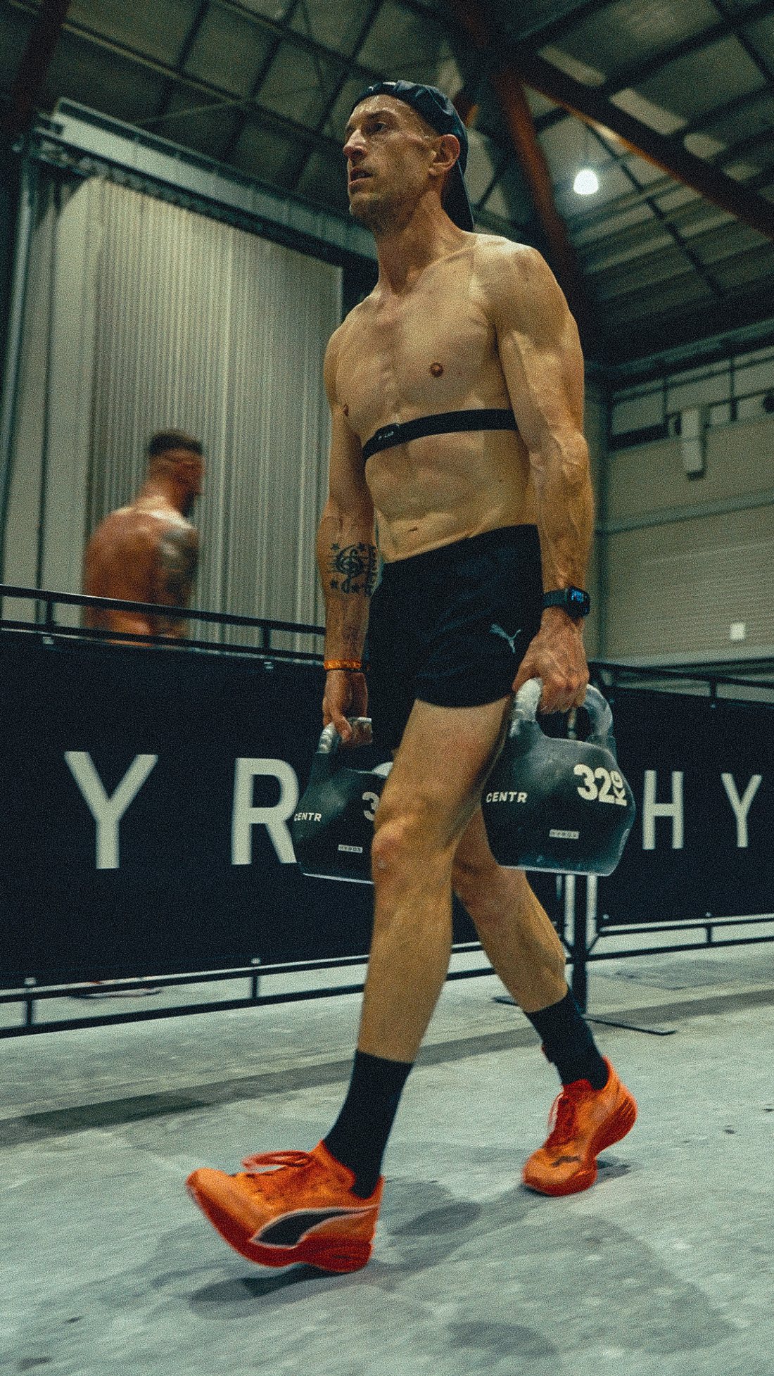 Matt Osborne carrying kettlebells during a Hyrox race, wearing a heart rate strap and a watch